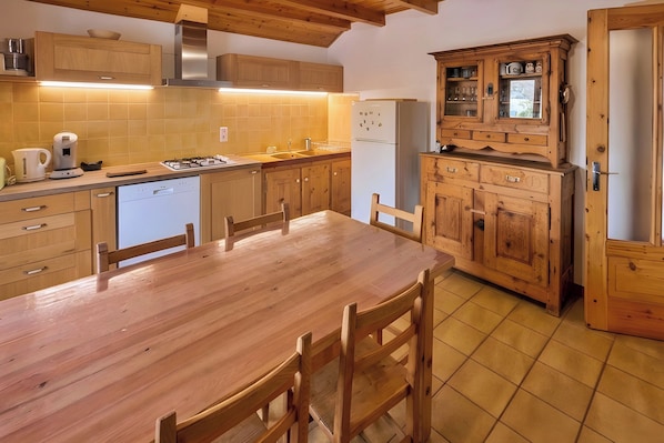 Eine Küche mit Holzausstattung, einem Esstisch, Stühlen, einem Herd und einem Kühlschrank.