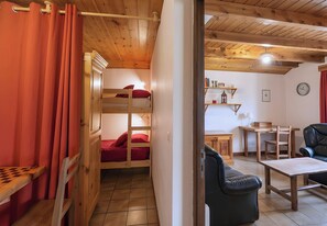 Une chambre avec un lit superposé, un bureau, une chaise et une petite table.