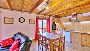 Una cuina acollidora amb armaris de fusta, una taula de dinar i una cortina vermella.