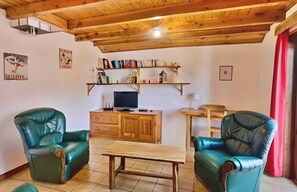 A living room with two green leather chairs, a wooden coffee table, a TV on a wooden cabinet, and bookshelves above. - Casa-La Carotto Appartement pour 6 dans chalet (Molines-en-Queyras)
