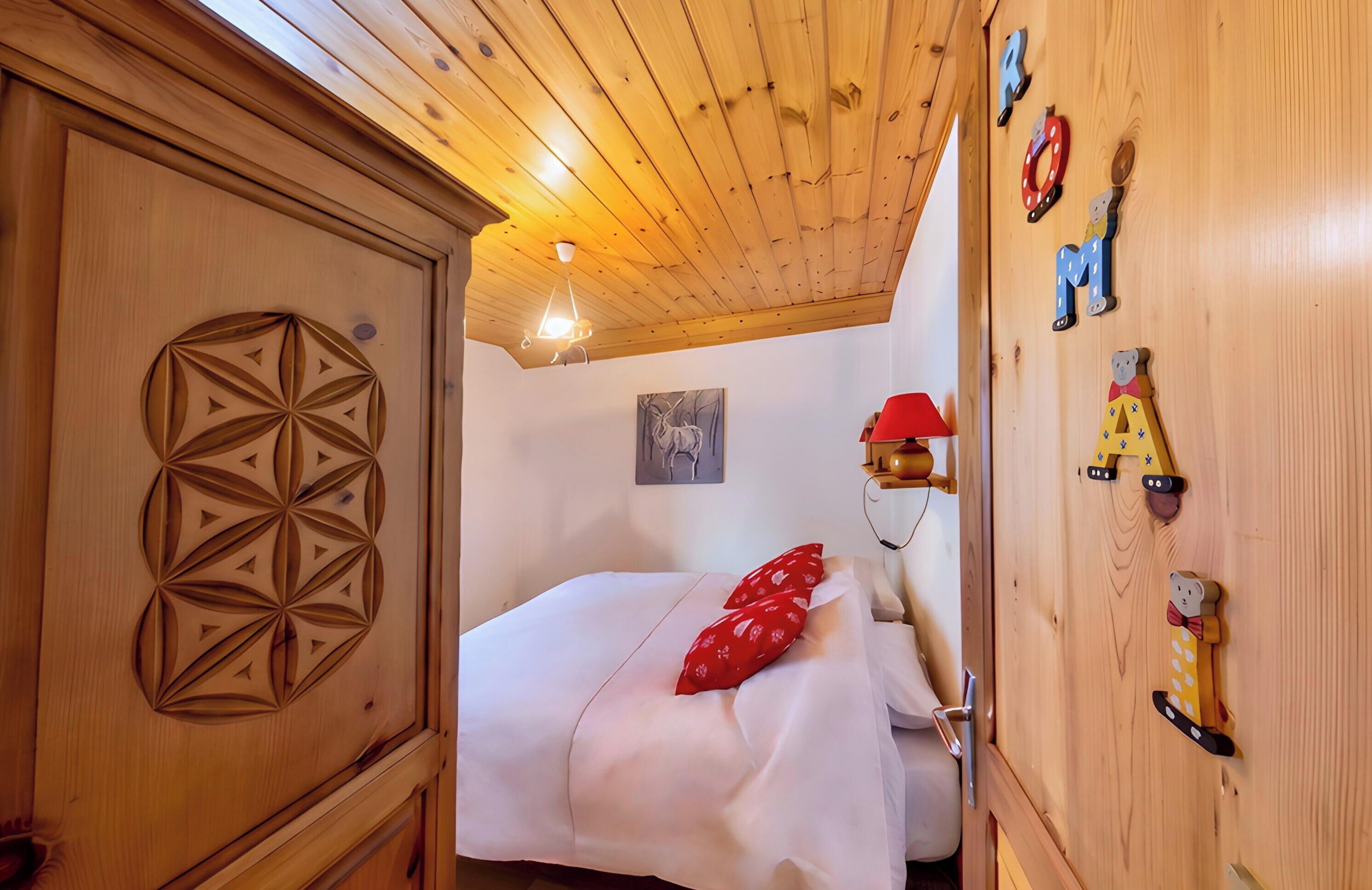Una stanza in legno con un letto, una parete decorata con lettere dell'alfabeto e una lampada a soffitto.