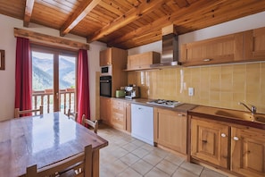 Une cuisine avec des meubles de rangement en bois, une cuisinière, un four à micro-ondes et un lave-vaisselle.