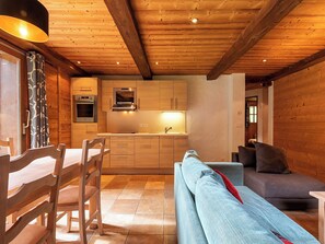 Interior de madeira com área de refeições, cozinha e espaço para sentar.