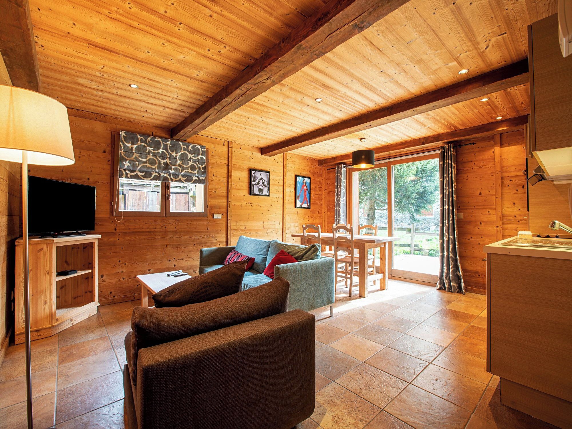 A wooden interior with a sofa, TV, and dining area.