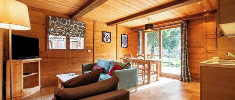 A wooden interior with a sofa, TV, and dining area.