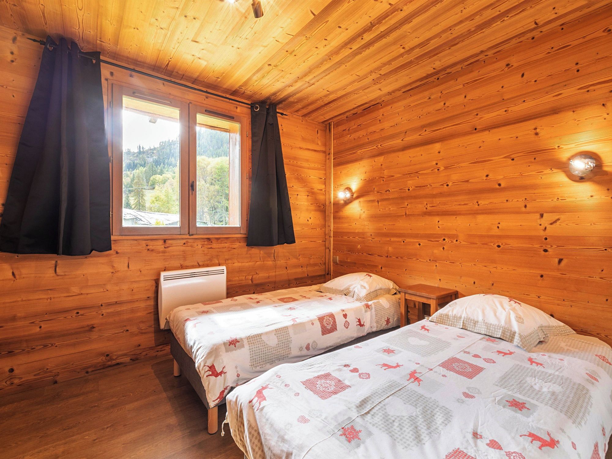 A wooden cabin room with two beds, a window, and a heater.