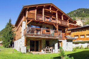 A two-story wooden chalet with balconies, stone foundation, and a mountain backdrop. - Casa-Chalet du Parc Cosy apartment in Tignes (Tignes)