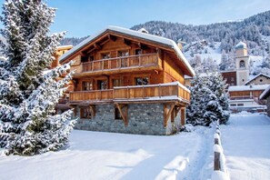 A multi-story wooden chalet with a stone foundation, surrounded by snow-covered trees and a mountainous backdrop. - Casa-Chalet du Parc Cosy apartment in Tignes (Tignes)