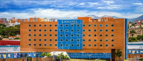 A hotel with a prominent blue sign, multiple floors, and a parking lot in front.