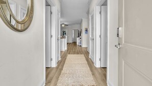 A hallway with white doors, a wooden floor, and a beige rug.