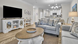 A living room with a grey sofa, a coffee table, a TV, and a ceiling fan.