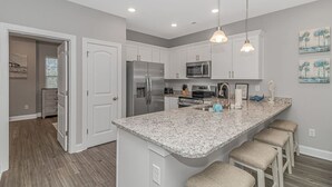 A modern kitchen with granite countertops, stainless steel appliances, and pendant lighting.