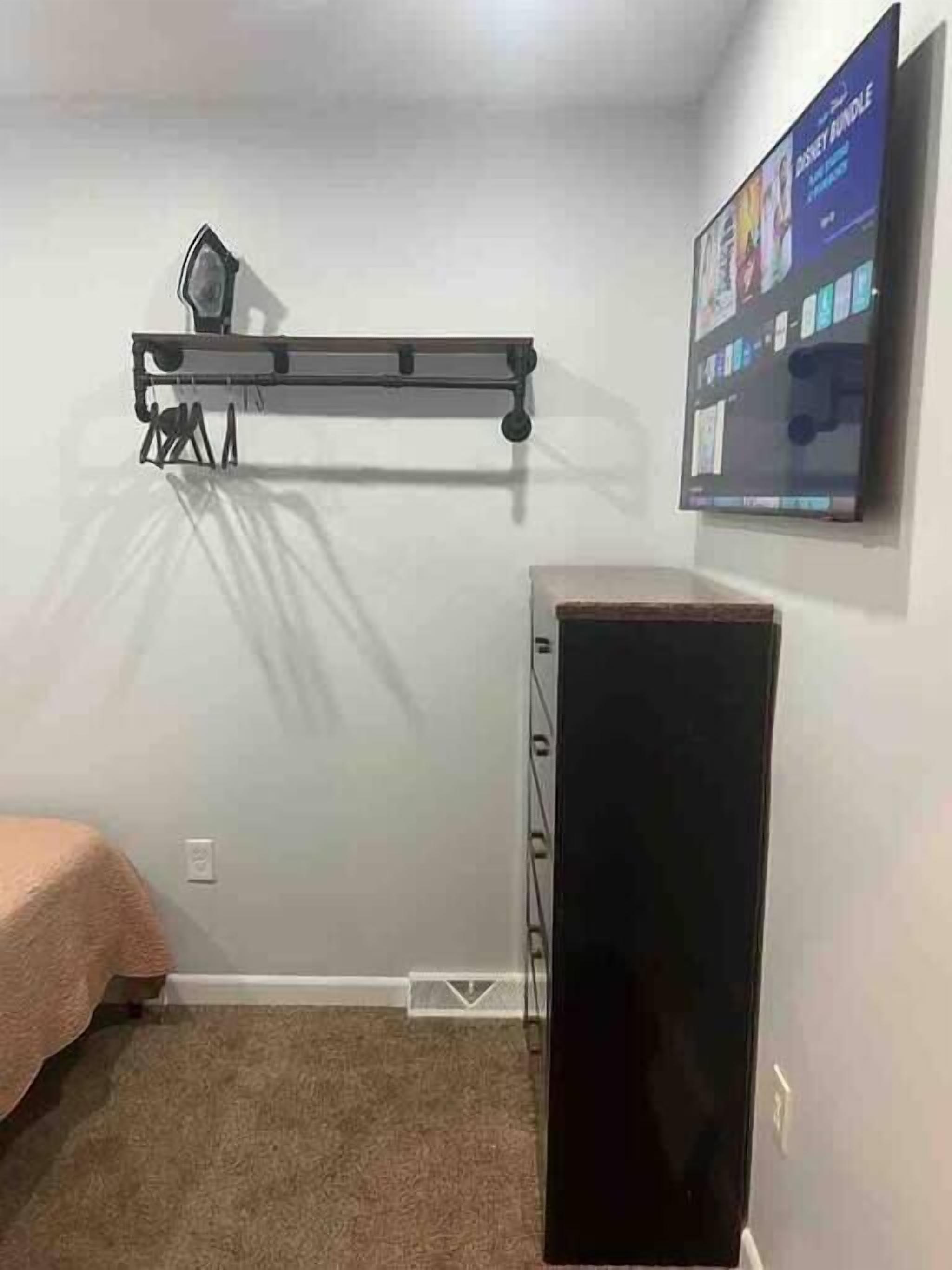 A room with a bed, a desk, and a TV mounted on the wall.