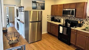 Una cucina moderna con elettrodomestici in acciaio inossidabile, pensili in legno e una parete rivestita in piastrelle.
