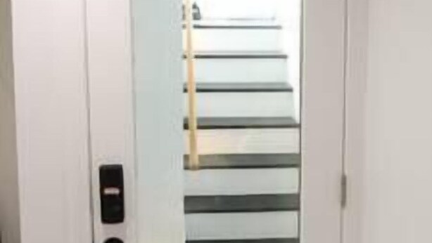 Una porta blanca amb un panell de vidre, que dona a una escala amb baranes de metall.