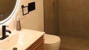 Un bany modern amb un mirall rodó, un rentapans i un vàter.