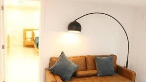Habitació amb un sofà marró, dos coixins i una làmpada de terra negra.