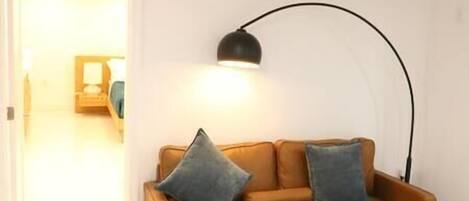 A room with a brown sofa, two pillows, and a black floor lamp.