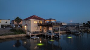 A waterfront house with a dock, a covered deck, and a boat. - Discover Your Dream Waterfront Getaway in Port Isabel, Texas! (Port Isabel)