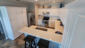 A modern kitchen with white cabinetry, stainless steel appliances, and a central island with stools. - Discover Your Dream Waterfront Getaway in Port Isabel, Texas! (Port Isabel)