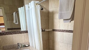 A bathroom with a shower, a sink, and a mirror. - Snowbird Motel (Bristol)