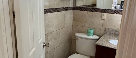 A bathroom with a toilet, sink, and towels stacked on the wall.