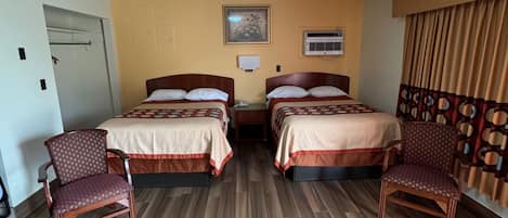 Ein Hotelzimmer mit zwei Betten, einer Deckenleuchte, einer Klimaanlage und einem gemusterten Vorhang.