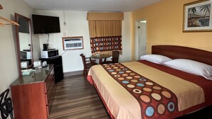 A hotel room with a bed, a desk, a chair, a television, and a window with curtains. - Snowbird Motel (Bristol)