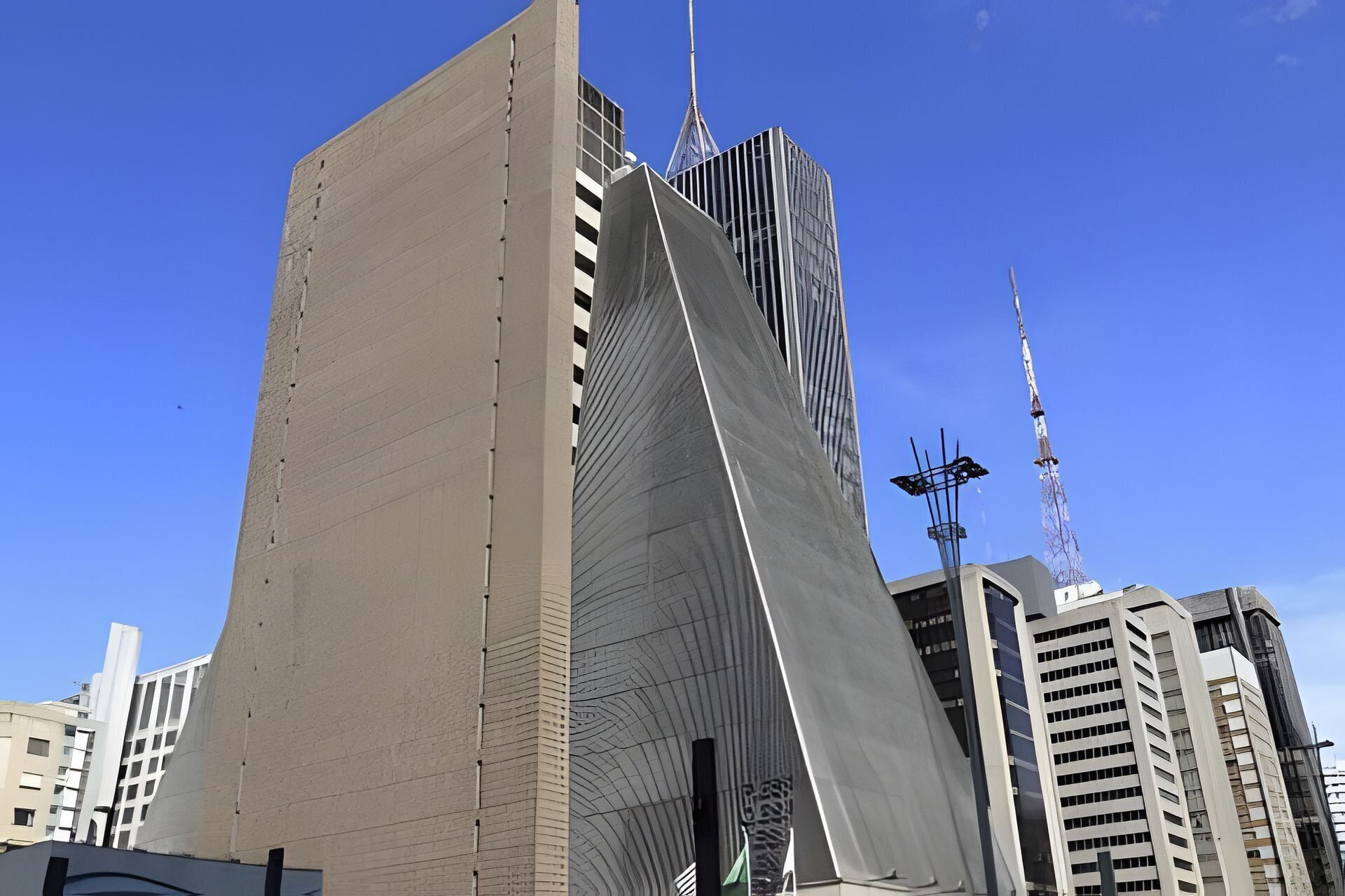 Ein modernes Gebäude mit einem markanten, winkligen Design, das sich durch eine auffällige geneigte Fassade und eine Reihe vertikaler Linien auszeichnet.