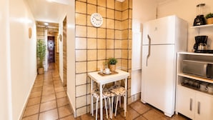 A kitchen with a white refrigerator, a microwave, and a coffee maker on the countertop. - Amazing sea view in Copacabana (Rio de Janeiro)