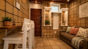 A cozy room with a wooden door, a white table with chairs, a brown sofa with cushions, and a wall-mounted shelf with a plant. - Sea view and bathtub in Copacabana, metro nearby (Rio de Janeiro)