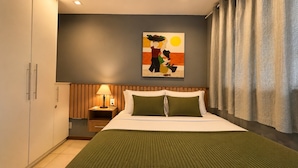 Een hotelkamer met een bed, nachtkastje, lamp en schilderij aan de muur.