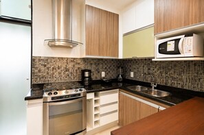Cocina compacta con estufa, microondas y cafetera.