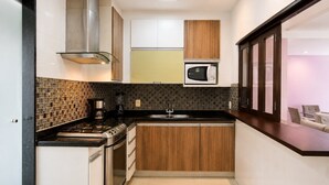 A compact kitchen with a microwave, stove, and sink. - Confortável 3Qts: Vista Lateral Mar (Rio de Janeiro)