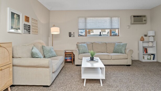 A living room with two beige sofas, a white coffee table, a small side table, a floor lamp, and a bookshelf. - Chic Central Nook in Great Falls (Great Falls)