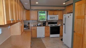 A compact kitchen with wooden cabinets, a microwave, a stove, and a refrigerator. - Five W Ranch -Sugar Hill Farm location- Private, Five Minutes From Downtown!

 (Saint Marys)