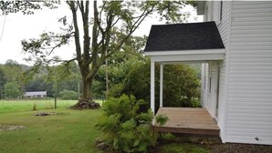 A white house with a covered porch and a large tree in the yard. - Five W Ranch -Sugar Hill Farm location- Private, Five Minutes From Downtown!

 (Saint Marys)