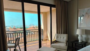 Ein Hotelzimmer mit Balkon, Bett, Sessel und Tisch.