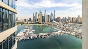 A high-rise building with a marina and city skyline in the background.