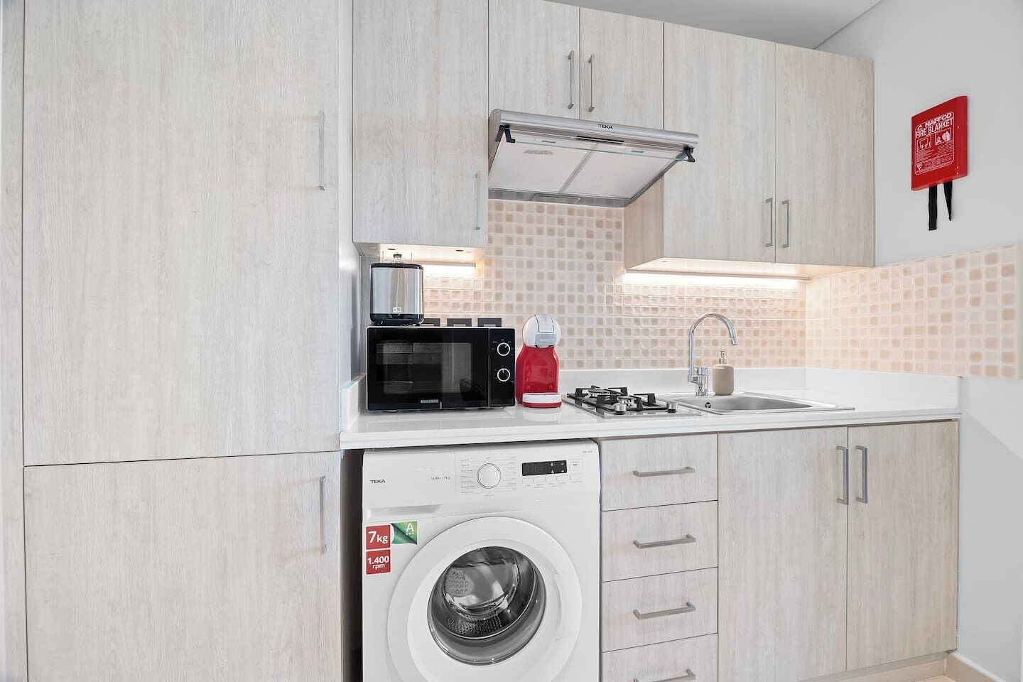 A compact kitchen with a microwave, toaster, and washing machine.