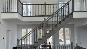 A spacious living area with a central staircase, a leather sofa, and a coffee table.