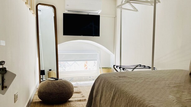 A bedroom with a bed, a large mirror, a television, and a window with a view. - Capo - Single Room (Butera Apartments Luxury) (Palermo)