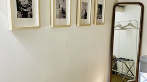 A hallway with framed black and white photographs on the wall, a mirror reflecting a clothing rack, and a window with a view of the outside. - Capo - Single Room (Butera Apartments Luxury) (Palermo)