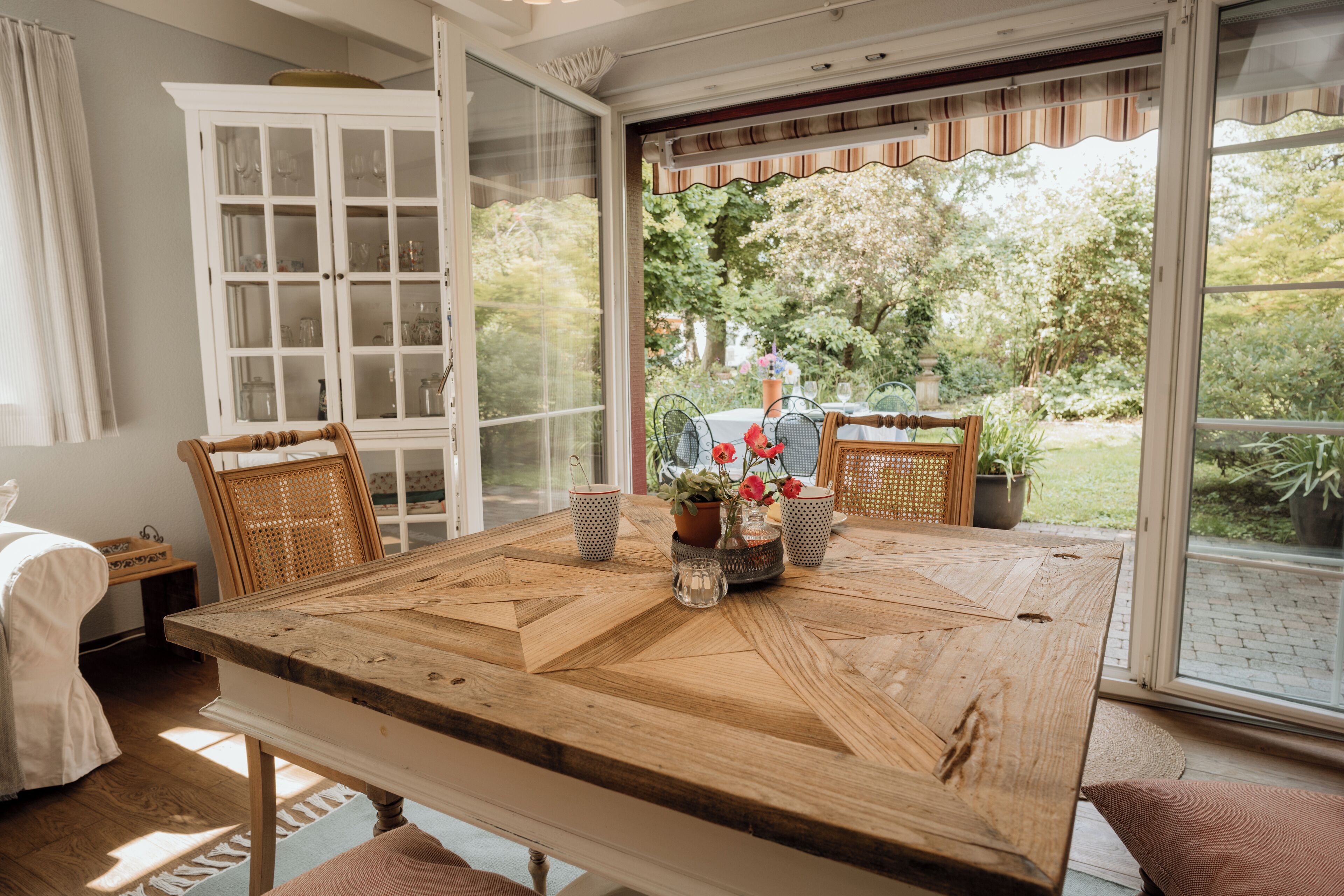 Un comedor con una mesa de madera, sillas y vistas al jardín a través de grandes ventanales.