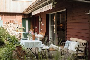 A wooden house with a patio, a table with chairs, and a bench.
