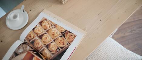 A wooden table with a book open displaying images of roses, a white ceramic cup, and a woven basket.