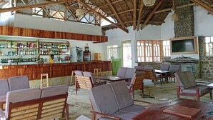 A rustic bar area with wooden furniture and a thatched roof. - Hillstone Safari Lodge (Kimana)