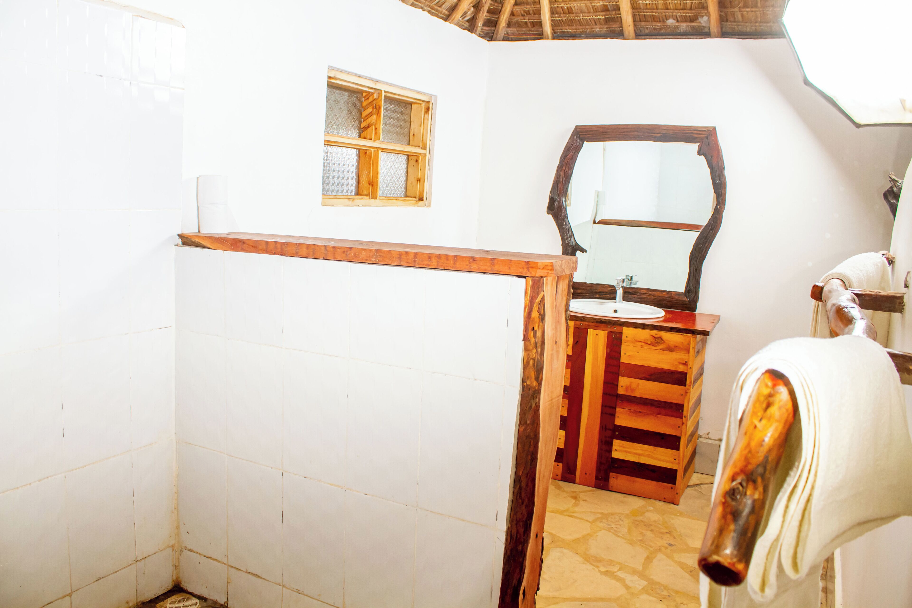 A bathroom with a wooden vanity, a mirror, and a shower area.