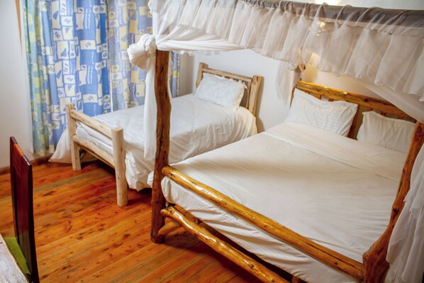 Una habitación con dos camas de madera, una con dosel y otra sin él.