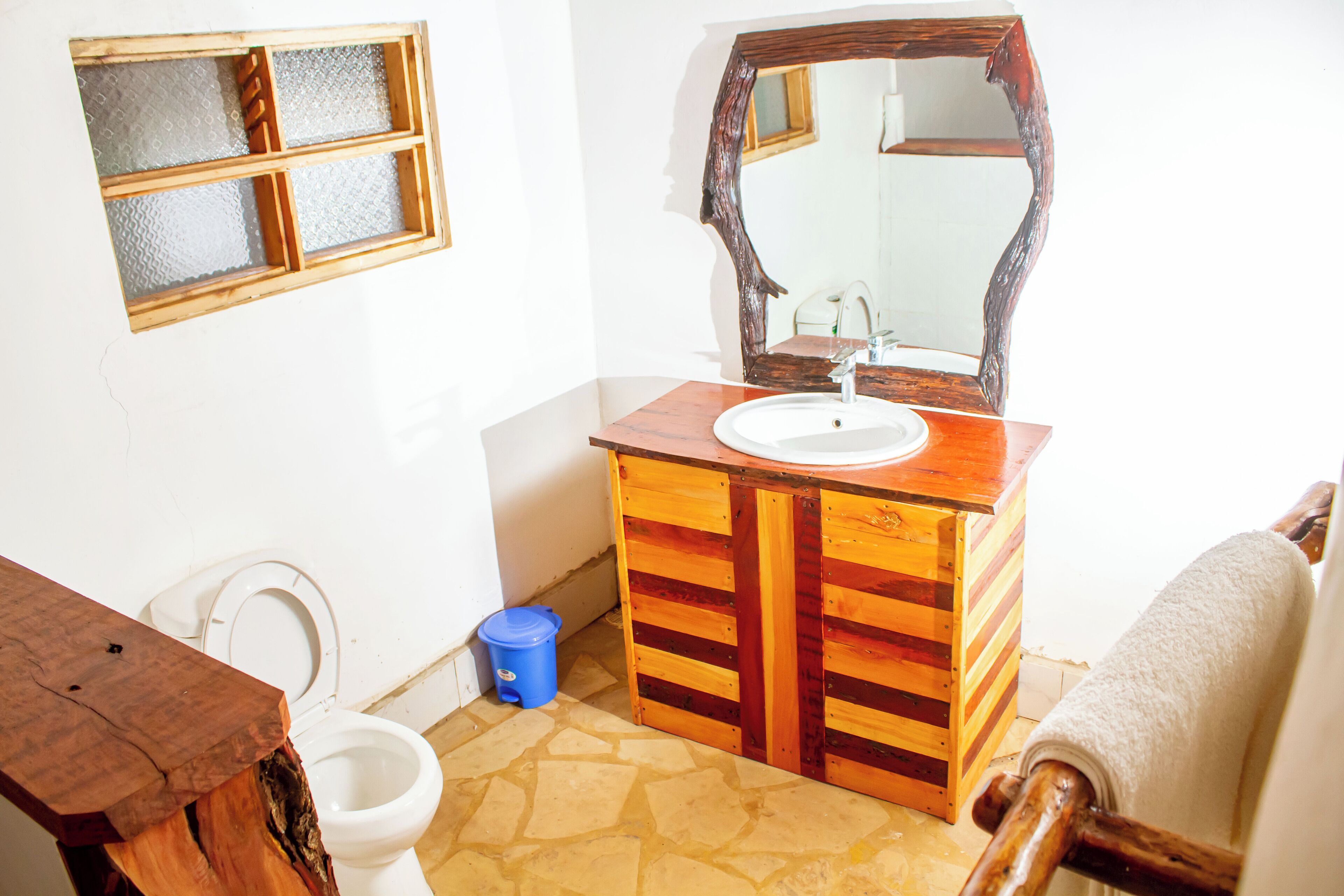 A bathroom with a wooden vanity, a white sink, a large mirror, and a toilet.